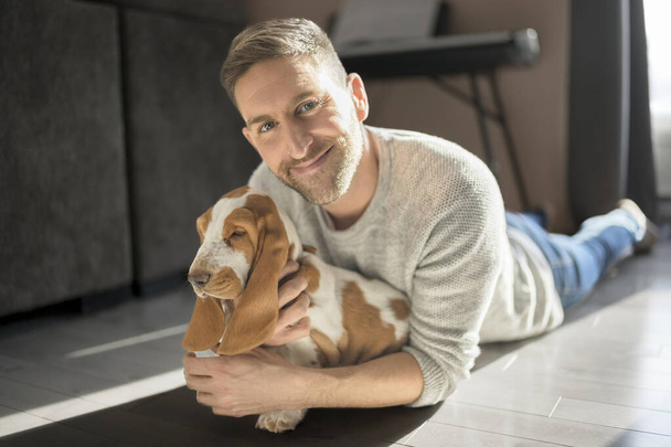 Man Playing With basset Pet Dog At Home on his apartment - Φωτογραφία, εικόνα