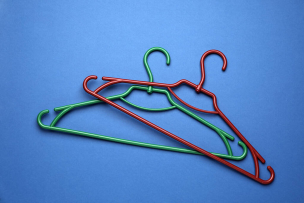 Empty clothes hangers on blue background, flat lay - 写真・画像