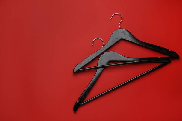 Empty clothes hangers on red background, flat lay. Space for text - Φωτογραφία, εικόνα