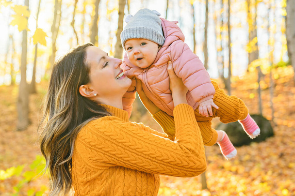Baby daughter and her mother in the autumn season in park - Foto, imagen