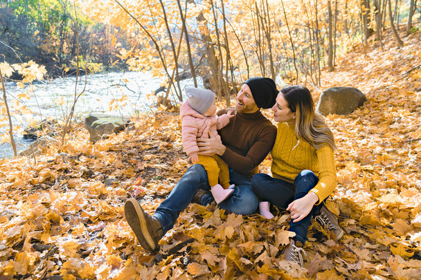 Baby daughter and her parents in the autumn season in park - Zdjęcie, obraz