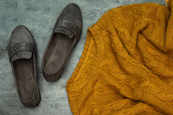 El concepto de confort en el hogar, calidez y calidez suéter y zapatos planos grises en la mesa de madera - Foto, imagen