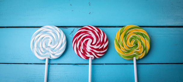 Colorful lollipops on a blue painted wooden background - Фото, изображение