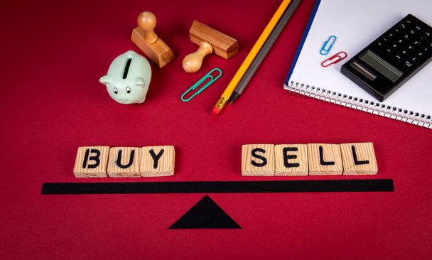Buy and Sell balance concept. Piggy bank and office supplies on a red background - 写真・画像