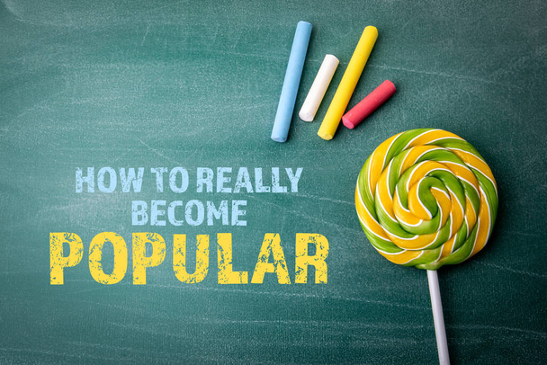 How To Really Become Popular. Colored pieces of chalk and candy on a green board - Foto, imagen