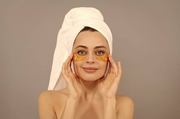 молода жінка з махровим рушником використовує лицьову золоту пляму для шкіри, шкіри
 - Фото, зображення