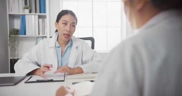 Медицинская команда молодых азиатских женщин-врачей в белой медицинской форме с помощью ноутбука обсуждает результаты компьютерной томографии в больничном офисе. Консультации и терапия. - Кадры, видео