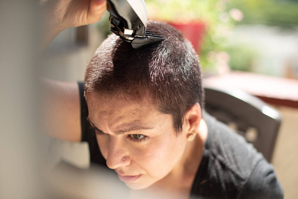 bezorgde jonge vrouw scheren uw hoofd met een scheermes thuis leven stijl - Foto, afbeelding