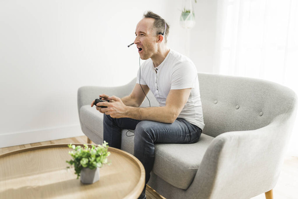 Concentrated man having fun with video games while on a sofa - 写真・画像