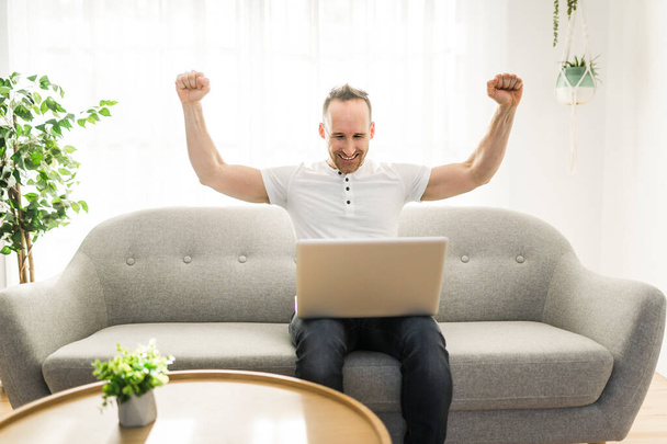 mies onnellinen ja menestys työskentelee tietokoneen kannettavan tietokoneen kotona - Valokuva, kuva