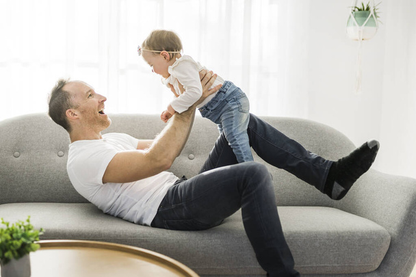 Отец играет с милой маленькой дочкой на диване - Фото, изображение