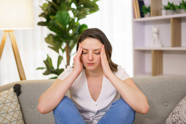 woman feels pain in head sit on sofa - Фото, изображение