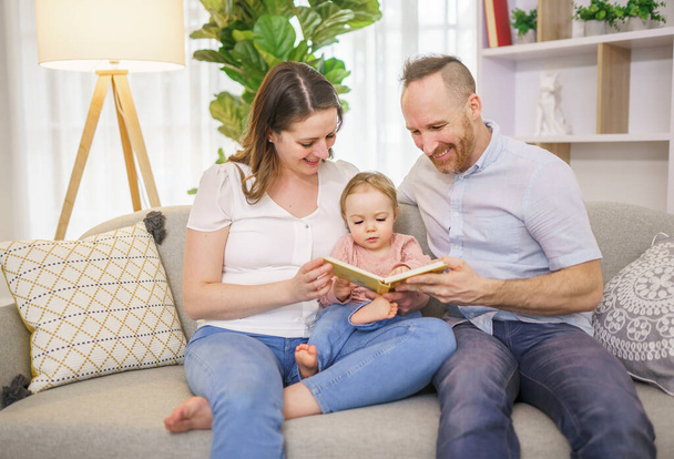 family is reading a book to her cute daughter. - Foto, Bild