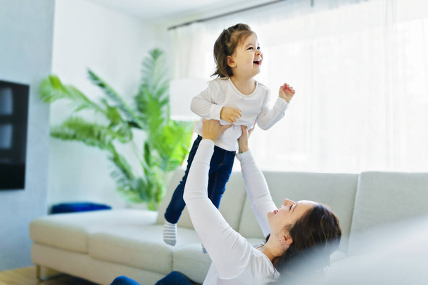 Mother with her daughter having fun in living room at home - Φωτογραφία, εικόνα