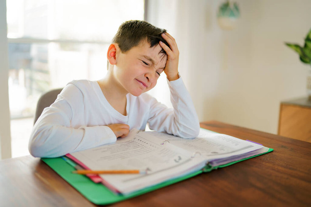 Thinking child bored and frustrated and fed up doing his homework - 写真・画像