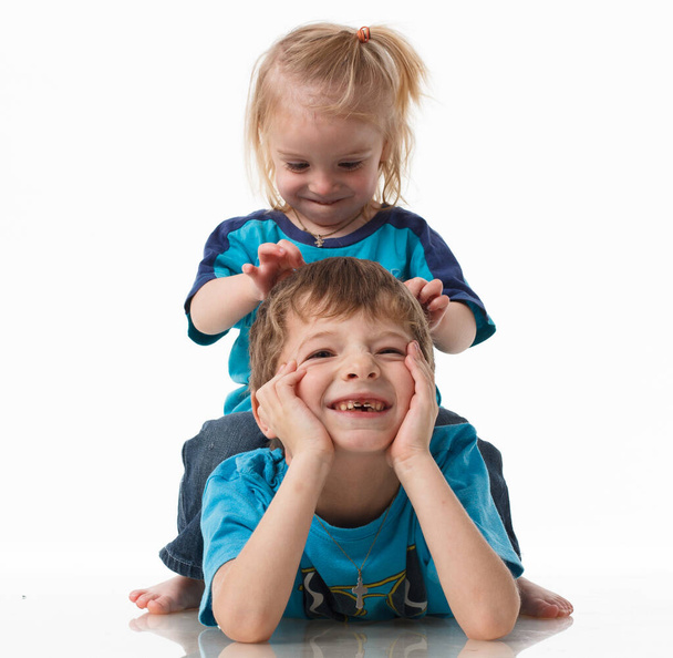 Πορτρέτο ενός αδελφού και μιας αδελφής, σγουρά ξανθιά με μπλε μάτια γελώντας χαρούμενα σε λευκό φόντο. Παιδικά συναισθήματα, ευτυχία, χαρά, διασκέδαση. Όμορφα χαριτωμένα παιδιά. Φιλία. - Φωτογραφία, εικόνα