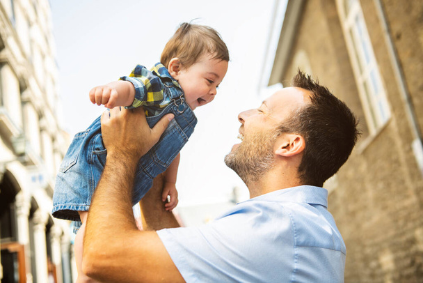 little baby son with father in city hagging and smiling, casual look outside - 写真・画像