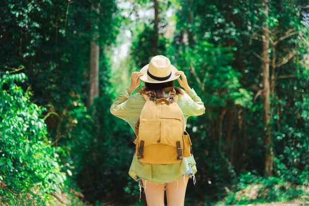 woman traveler with backpack holding hat and looking at amazing mountains and forest, wanderlust travel concept, space for text, atmospheric epic moment - Foto, imagen