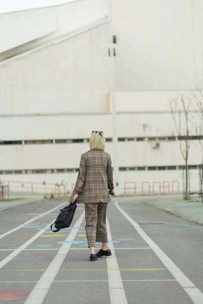Beautiful businesswoman is walking towards the company while turning - 写真・画像