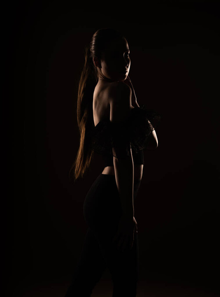 Beautiful silhouette of an attractive girl standing in the studio - Foto, Bild