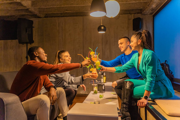 Group of multiracial best friends are smiling and doing cheers with their drinks - Фото, изображение