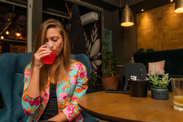 Attractive and beautiful young lady is drinking her cocktail - Photo, Image