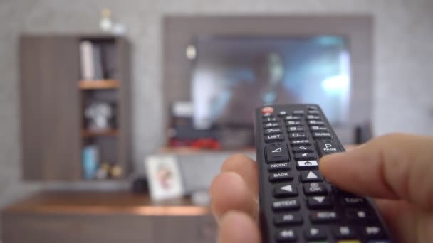 Egy kéz távirányítóval. 4K Férfi kéz távirányítóval TV csatornát vált. - Felvétel, videó