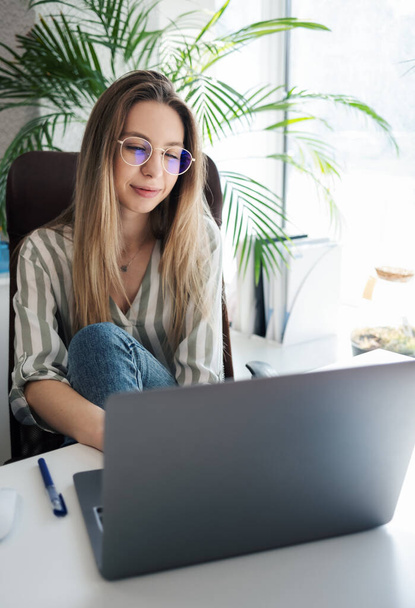 Fiatal nő dolgozik egy számítógépen az irodájában - Fotó, kép