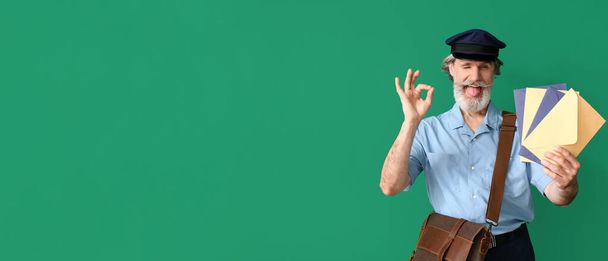 Handsome old postman showing OK on green background with space for text - Photo, image