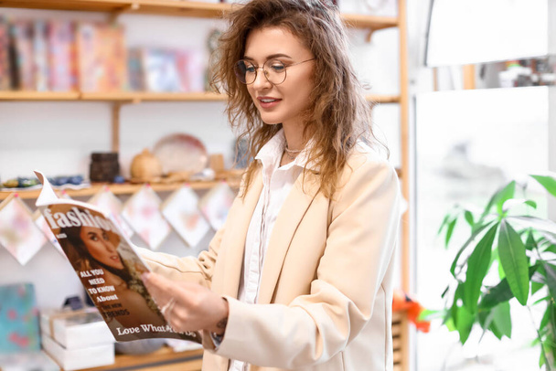 Vrouwelijke ondernemer met tijdschrift in haar winkel - Foto, afbeelding