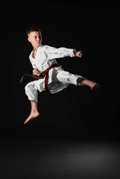 Junge übt Karate auf dunklem Hintergrund - Foto, Bild