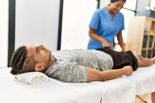 Nuori latino fysioterapisti nainen tehdä rehab hoito latino mies klinikalla. - Valokuva, kuva