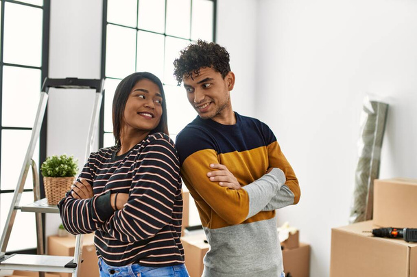 Молодая латинская пара улыбается счастливо стоя в новом доме. - Фото, изображение