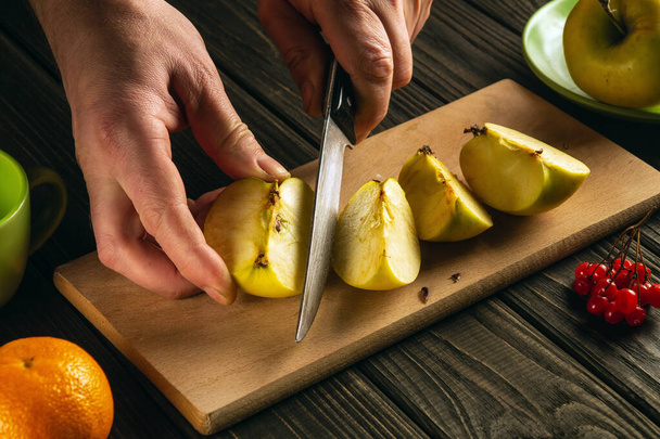 Hands of a chef with a knife cutting fresh apples on a cutting board. Fruit diet for a set of vitamins. Free space for advertising - Foto, Bild