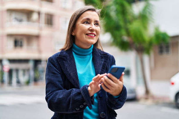 Жінка середнього віку керівник бізнесу, використовуючи смартфон на вулиці
 - Фото, зображення