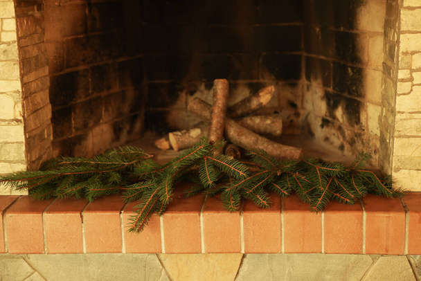 Fireplace with firewood and fir twigs without fire - Foto, afbeelding