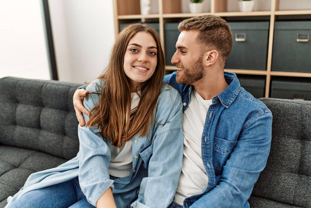 Young caucasian couple sitting on the sofa hugging at home. - Photo, Image