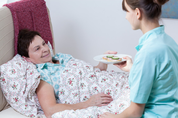 Nurse giving patient meal - Foto, afbeelding