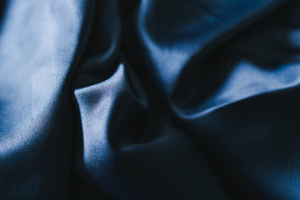 luxurious navy blue silk or satin fabric close-up for bedding or clothes, with soft wrinkle and light shining on it  - 写真・画像