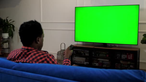 Zöld képernyős TV Afrikai amerikai férfi nézi TV chroma kulcs mock up kijelző - Felvétel, videó