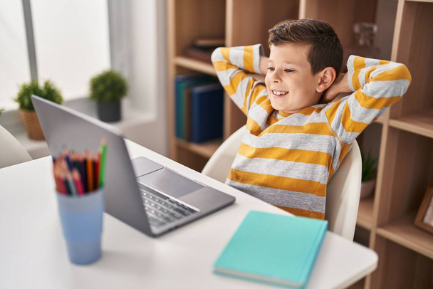 Vaalea lapsi käyttää kannettavaa tietokonetta istuu pöydällä kotona - Valokuva, kuva