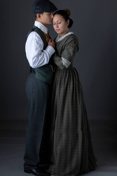 A romantic working class Victorian couple together against a grey studio backdrop - Fotó, kép