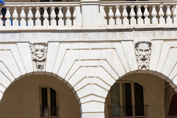 Brescia. Medieval Broletto Palace (Palazzo Broletto or Palazzo del Governo), XII-XXI century. Two white stone arches with keystones and grotesque human masks of gargoyles. Lombardy, Italy, Europe. - Zdjęcie, obraz