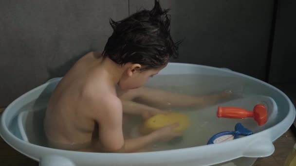 A fiú, aki a sárga játékkacsával fürdik. Vizet fröcskölök. Csecsemőmosás és fürdés. Gyerekgondozás és higiénia. - Felvétel, videó