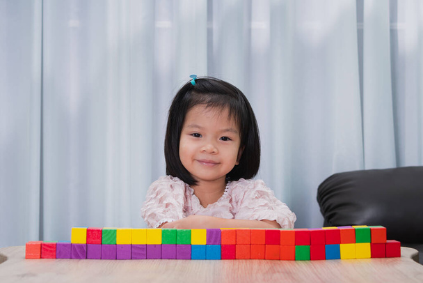 Image de portrait de 4-5 ans. Asiatique enfant assis sourire, avec un bloc de bois coloré place sur la table. École à domicile intérieure. En classe. Enfant mignon profiter de l'apprentissage par le jeu. Espace vide pour entrer le texte - Photo, image