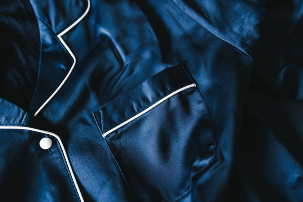 luxurious navy blue silk or satin tailored pyjama detail, fabric close-up with soft wrinkles and light shining on it  - 写真・画像