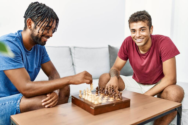 Two men friends playing chess sitting on sofa at home - Photo, Image