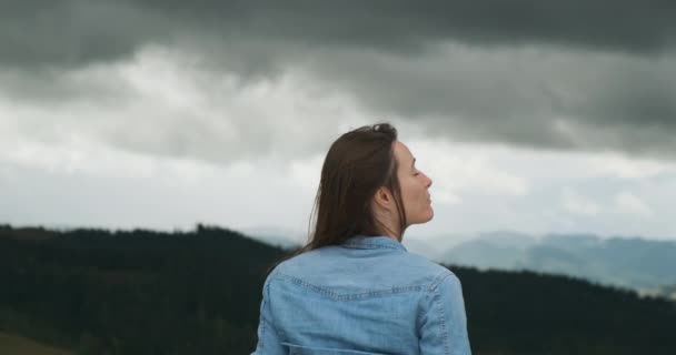 girl looks at the gray sky and the impending thunderstorm. Smiling and breathing in the fresh air. Rear view, medium shot - Filmmaterial, Video