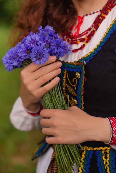 hands in traditional clothing belarus with cornflowers - Fotó, kép