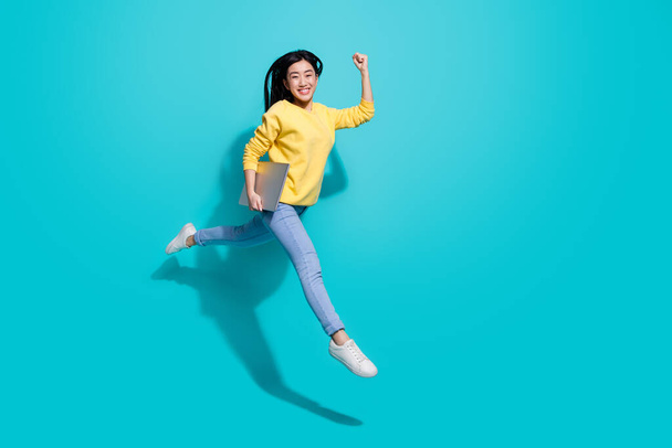 Full length photo of funny lucky lady dressed yellow sweater jumping runnig gadget empty space isolated turquoise color background - Фото, изображение